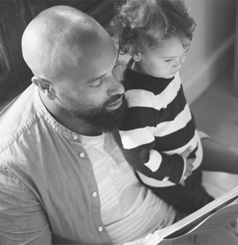 A man reads a book to his child. 