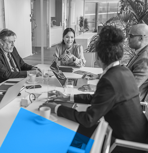 A group of office employees discuss business around a boardroom table. 