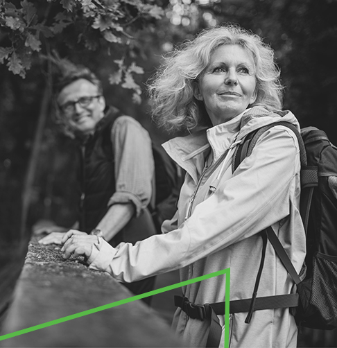 Woman and man dressed in outdoor gear, enjoying a hike in the woods.