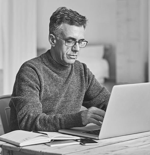 Man sitting at a desk studying his laptop screen. 